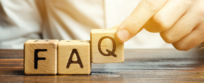 A hand is placing wooden blocks on a table that spell out FAQ