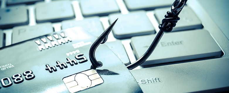 A fishing hook in a credit card sitting on top of a computer keyboard