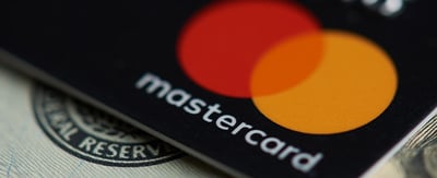 Close up image of a Mastercard payment card sitting atop paper money